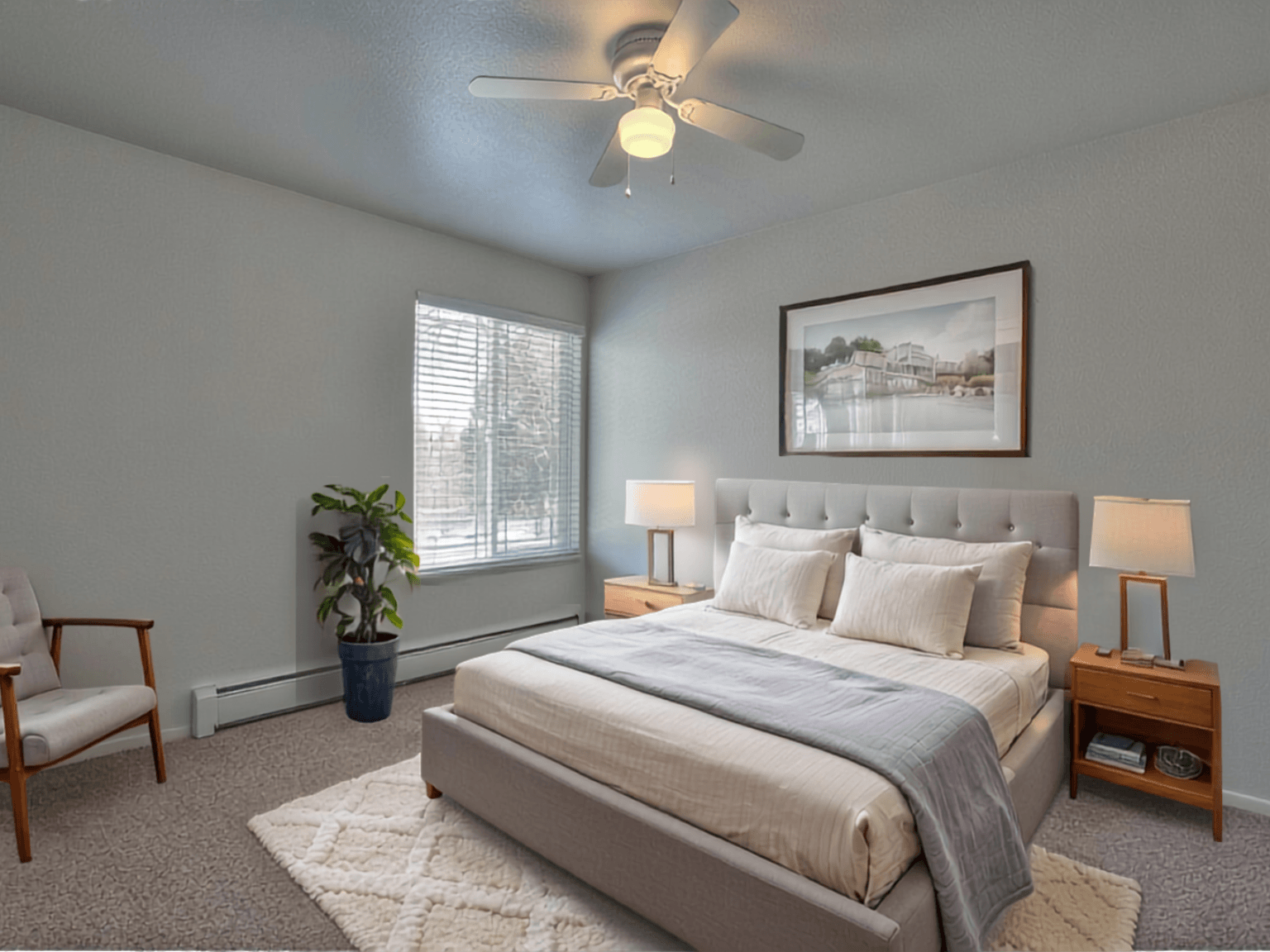 A bedroom with a large bed, a ceiling fan, and a potted plant.